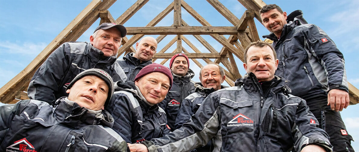 Das Team der Forch Bedachungen GmbH vor einem Dachstuhl